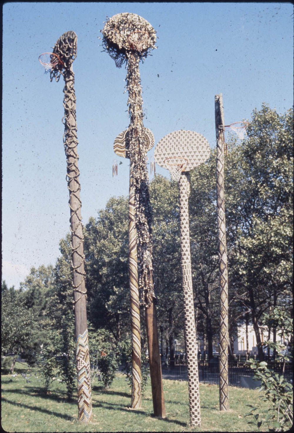 David Hammons, Higher Goals, 1986, Cadman Plaza Park, Brooklyn, photo by Pinkney Herbert and Jennifer Secor, courtesy of Public Art Fund. For Higher Goals, Hammons covered five telephone poles mounted with a basketball backboard and net with bottlecaps.  Hammons stated, “It takes five to play on a team, but there are thousands who want to play—not everyone will make it, but even if they don’t at least they tried.”<br/>